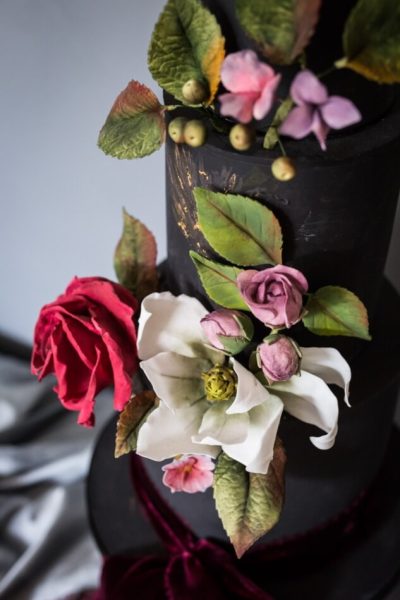 Devon wedding cake black with gold bas relief and sugar flowers